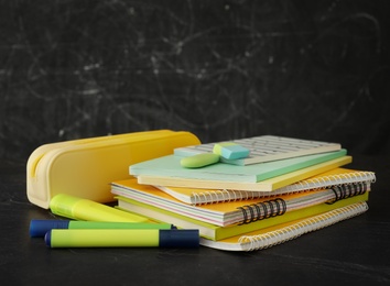 Photo of Different school stationery on stone table near blackboard. Back to school
