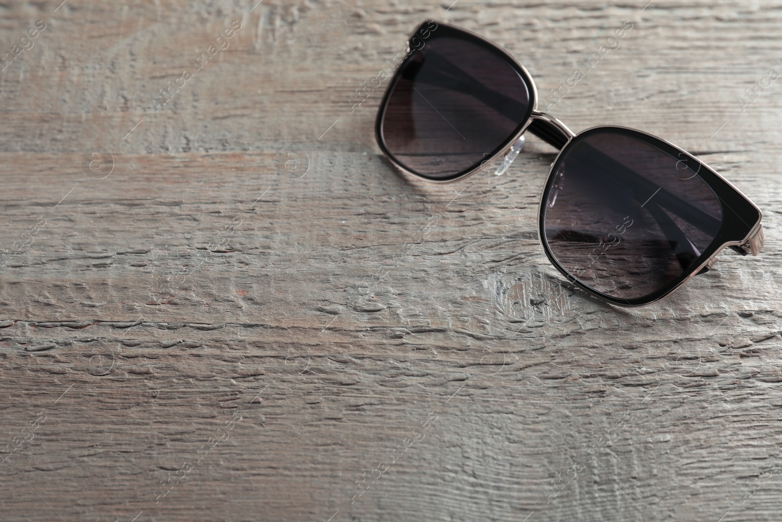 Photo of Stylish sunglasses on wooden background. Space for text