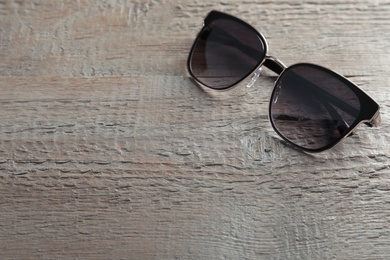 Photo of Stylish sunglasses on wooden background. Space for text