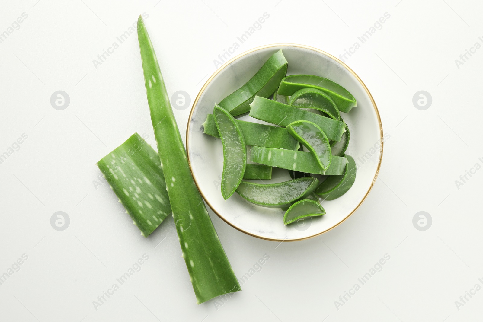 Photo of Bowl with fresh aloe vera pieces on white table, flat lay