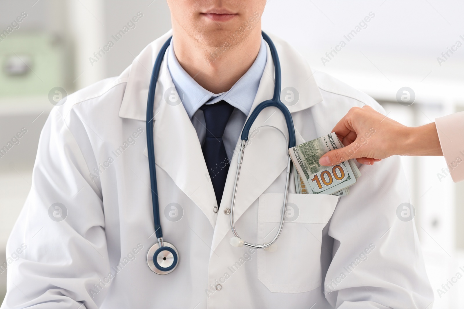 Photo of Patient putting bribe into doctor's pocket in clinic, closeup. Corrupted medicine