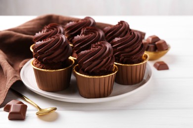 Delicious cupcake and chocolate pieces on white wooden table