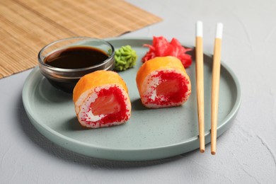 Delicious sushi rolls, soy sauce, wasabi, ginger and chopsticks on grey textured table, closeup