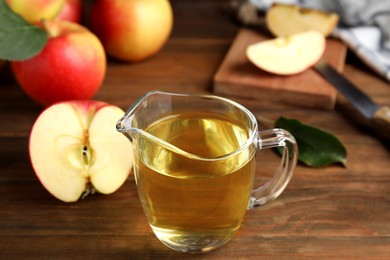 Photo of Natural apple vinegar and fresh fruits on wooden table