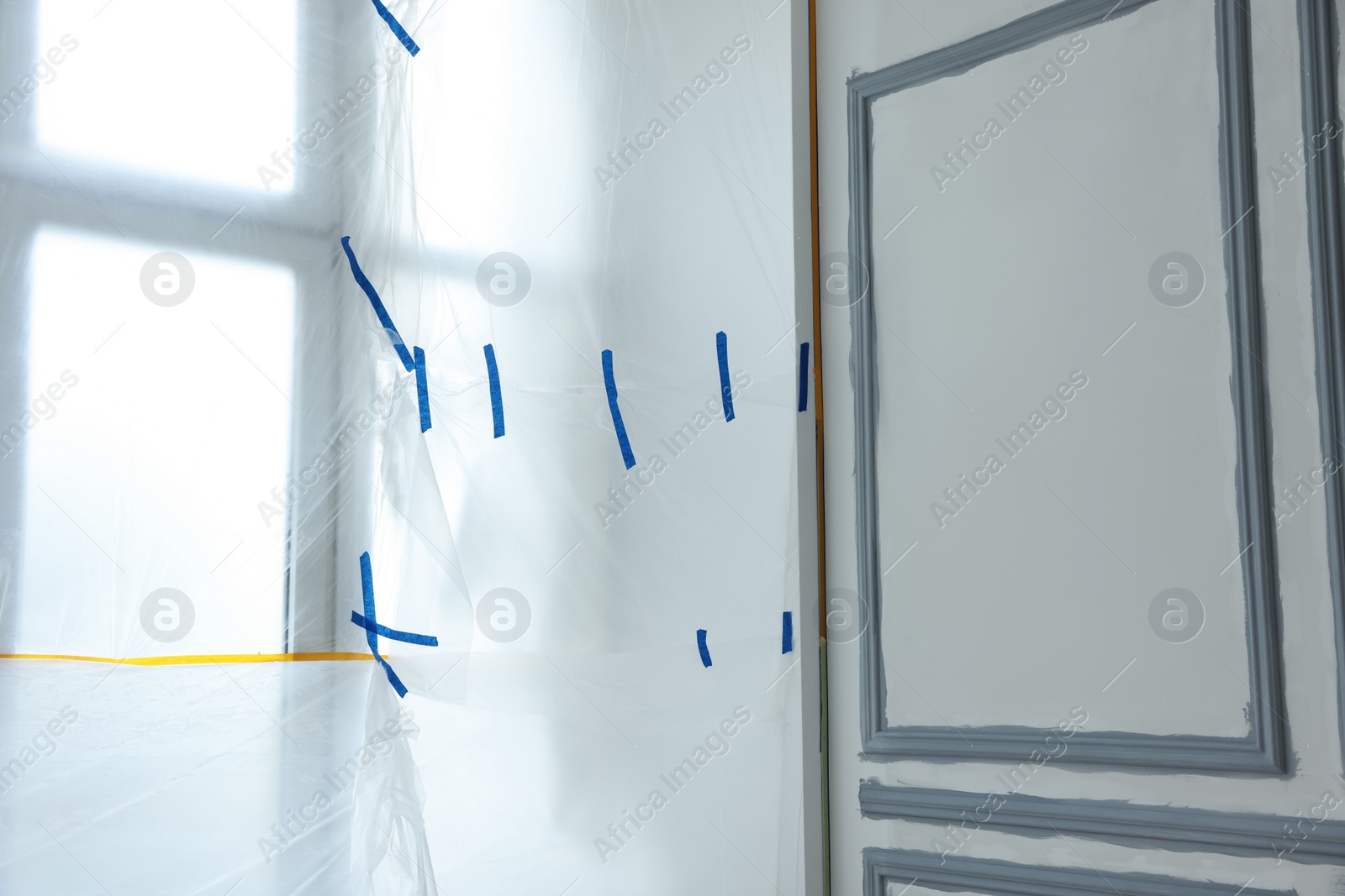 Photo of Window covered by plastic film and insulation tape indoors