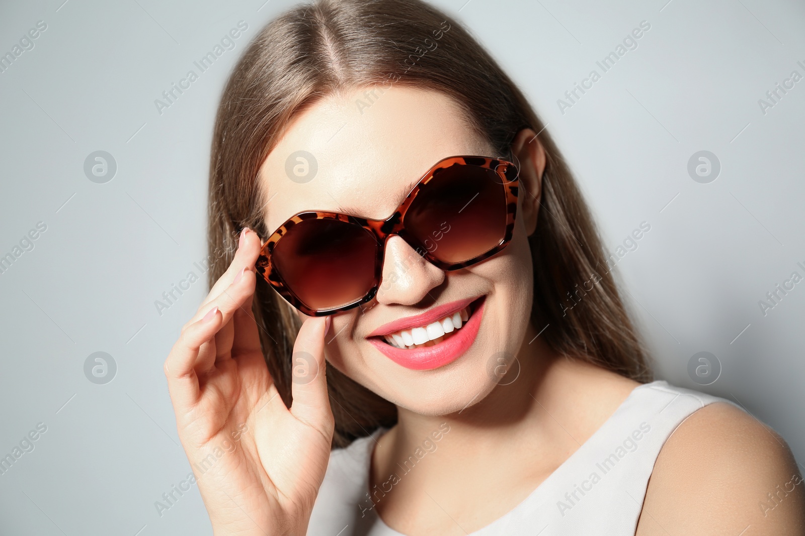 Photo of Young woman wearing stylish sunglasses on light grey background