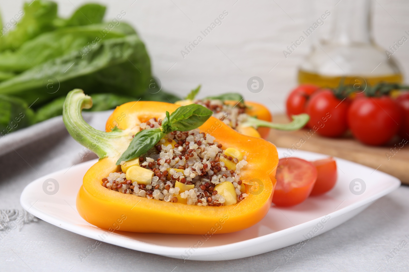 Photo of Quinoa stuffed bell pepper with basil on light table, closeup