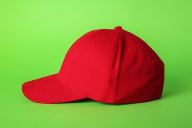 Photo of Stylish red baseball cap on light green background