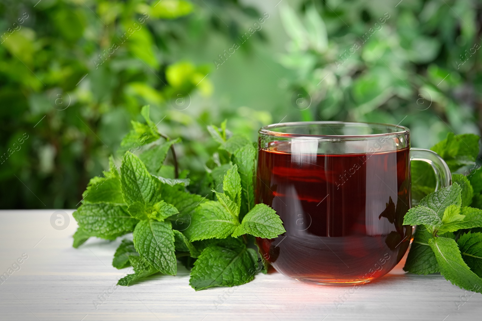 Photo of Fresh tea with mint leaves on white wooden table