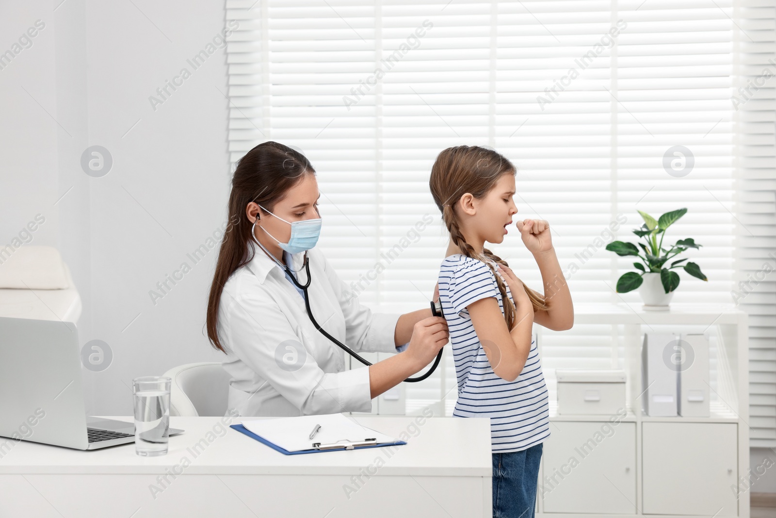 Photo of Doctor examining coughing girl in hospital. Cold symptoms