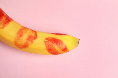 Top view of fresh banana with red lipstick marks on pink background, space for text. Oral sex concept