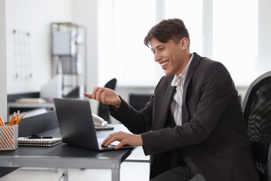 Man using video chat during webinar at table in office