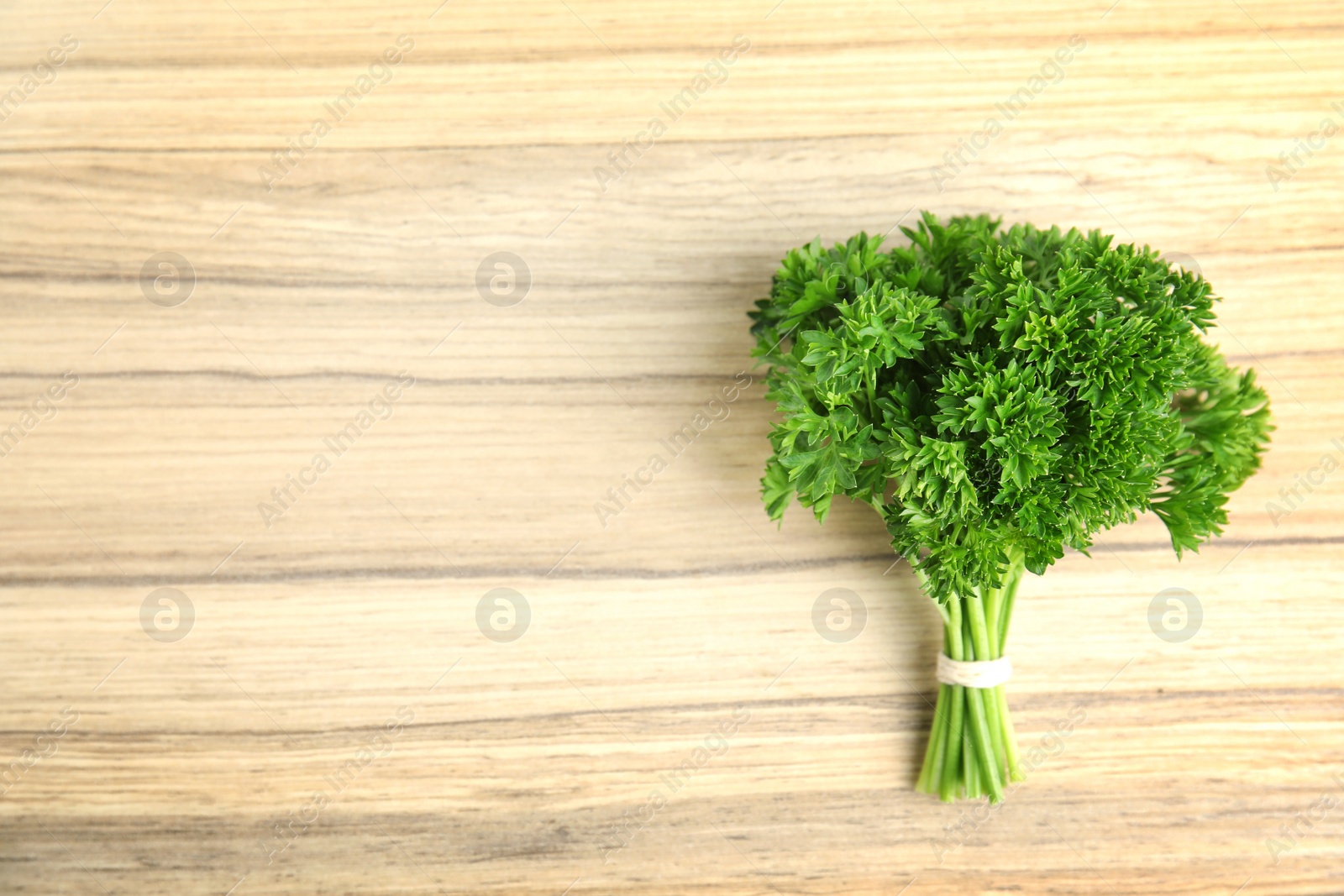 Photo of Bunch of fresh green parsley on wooden background, top view. Space for text