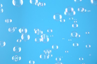 Photo of Beautiful transparent soap bubbles on light blue background