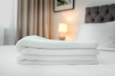 Stack of towels on bed in modern hotel room