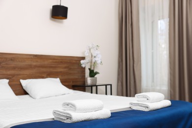 Photo of Clean folded towels on bed in hotel room