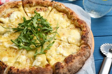 Photo of Tasty cheese pizza  with arugula on blue wooden table, closeup view