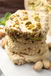 Photo of Pieces of tasty halva with pistachios on table, closeup