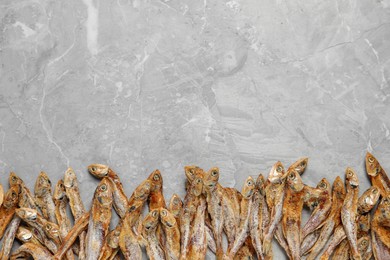 Photo of Tasty dried anchovies on light grey marble table, flat lay. Space for text