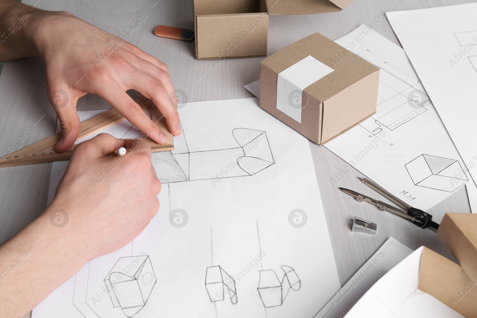 Photo of Man creating packaging design at light wooden table, closeup