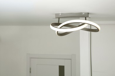 White ceiling with stylish lamp in room. Space for text