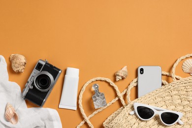 Photo of Flat lay composition with wicker bag and other beach accessories on orange background. Space for text