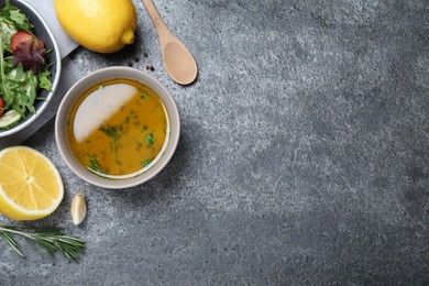 Photo of Bowl with lemon dressing near salad on grey table, flat lay with space for text. Delicious salad dressing