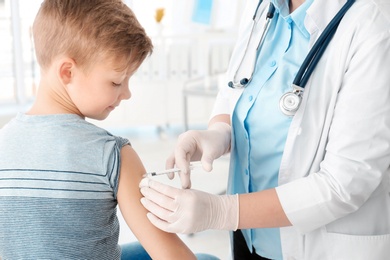 Photo of Doctor vaccinating little boy in hospital