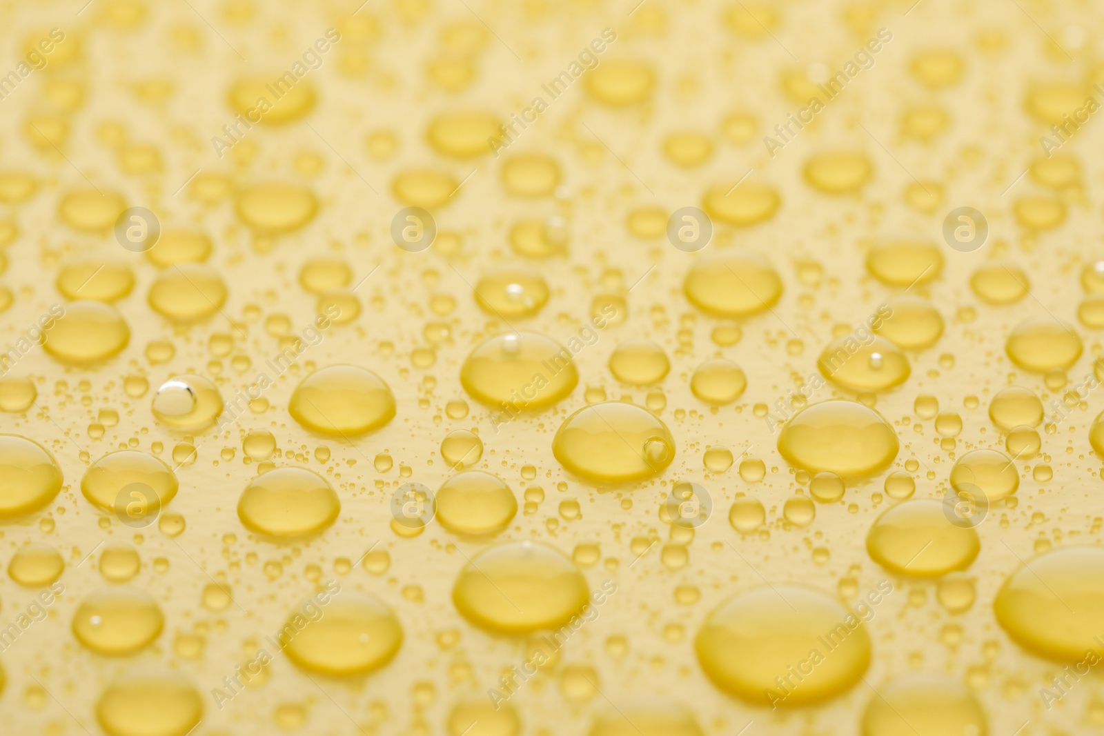 Photo of Water drops on yellow background, closeup view