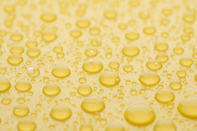 Photo of Water drops on yellow background, closeup view