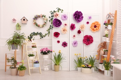 Photo of Easter photo zone with plants and paper flowers indoors