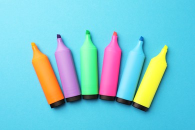 Photo of Bright markers on light blue background, flat lay