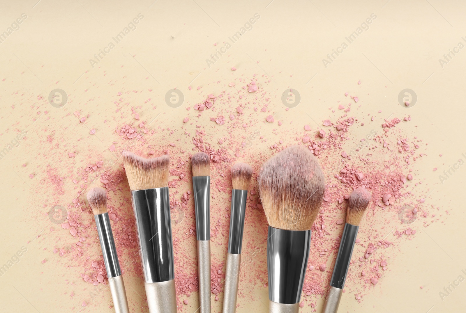 Photo of Makeup brushes and scattered eye shadow on beige background, flat lay. Space for text