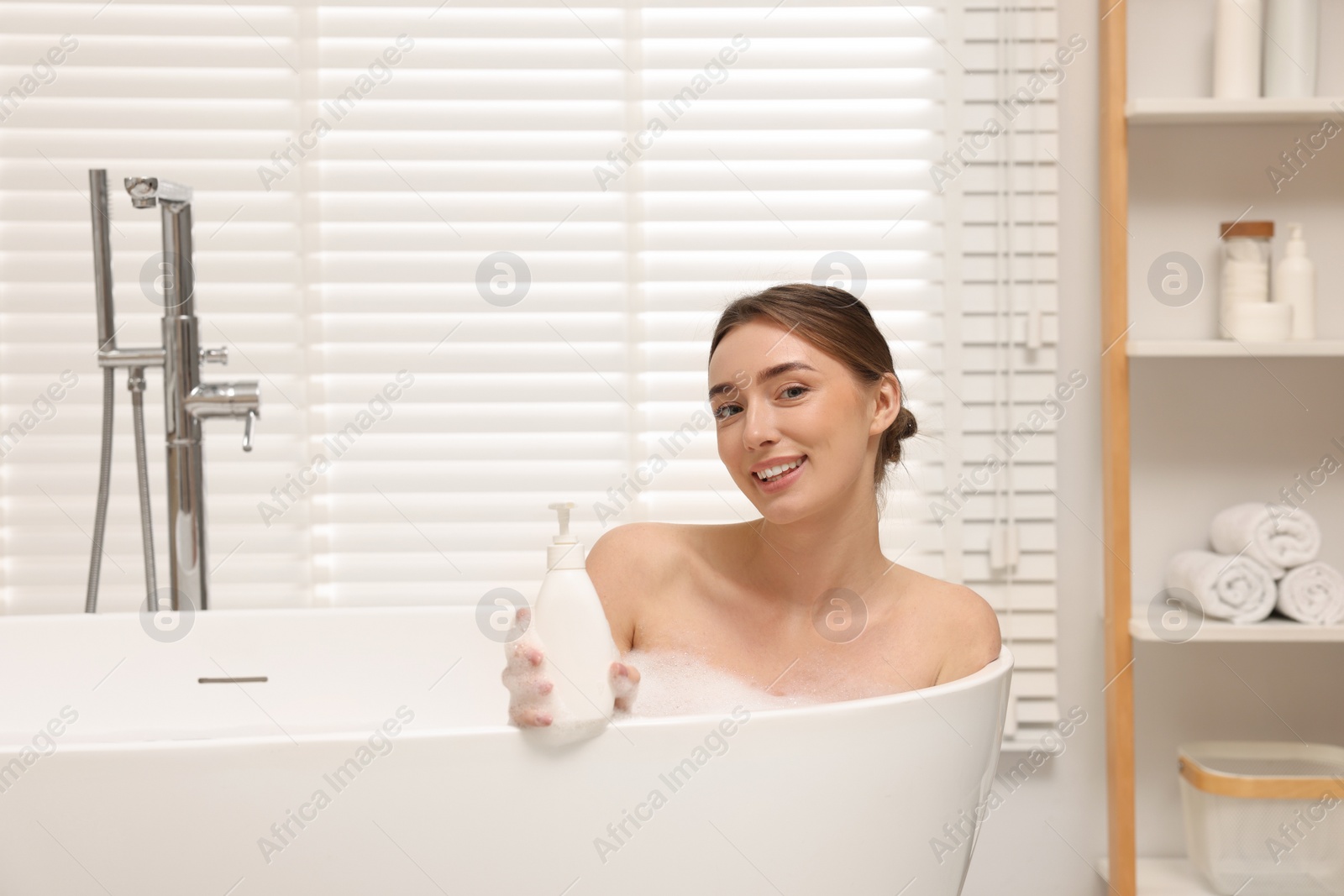 Photo of Woman taking bath with shower gel in bathroom