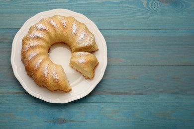 Photo of Delicious freshly baked sponge cake on light blue wooden table, top view. Space for text