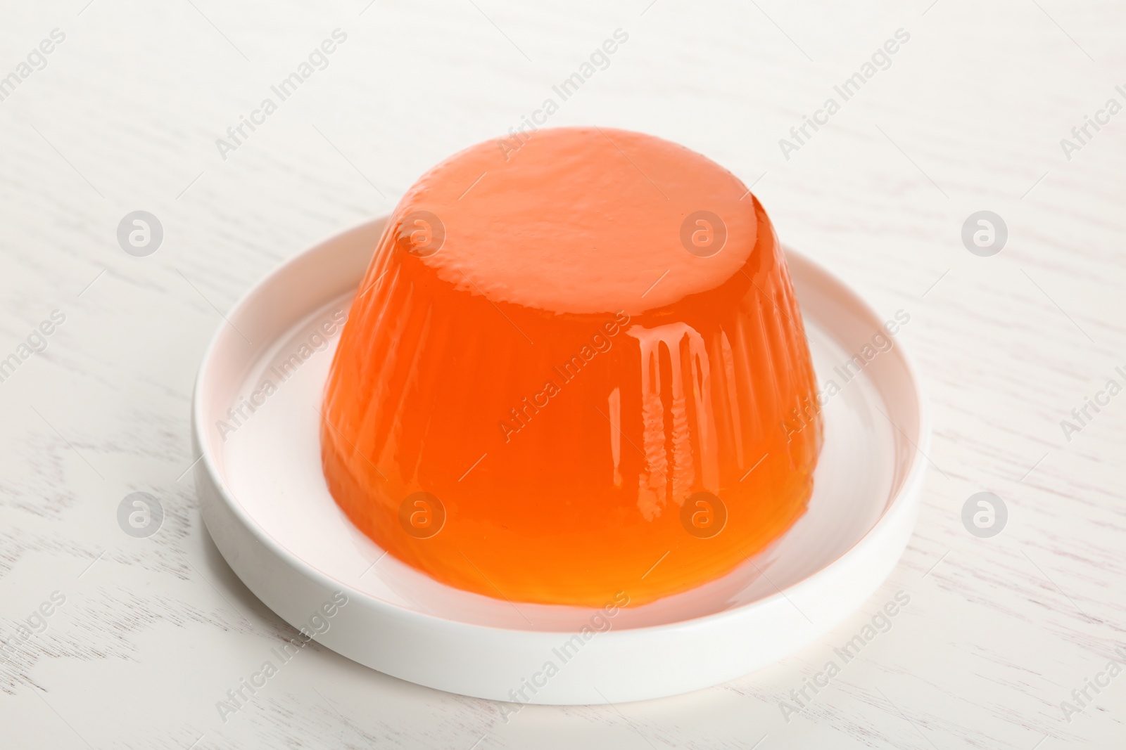 Photo of Plate with tasty fruit jelly on white wooden table