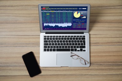 Image of Modern laptop with electronic trading platform application on wooden table, flat lay. Stock exchange