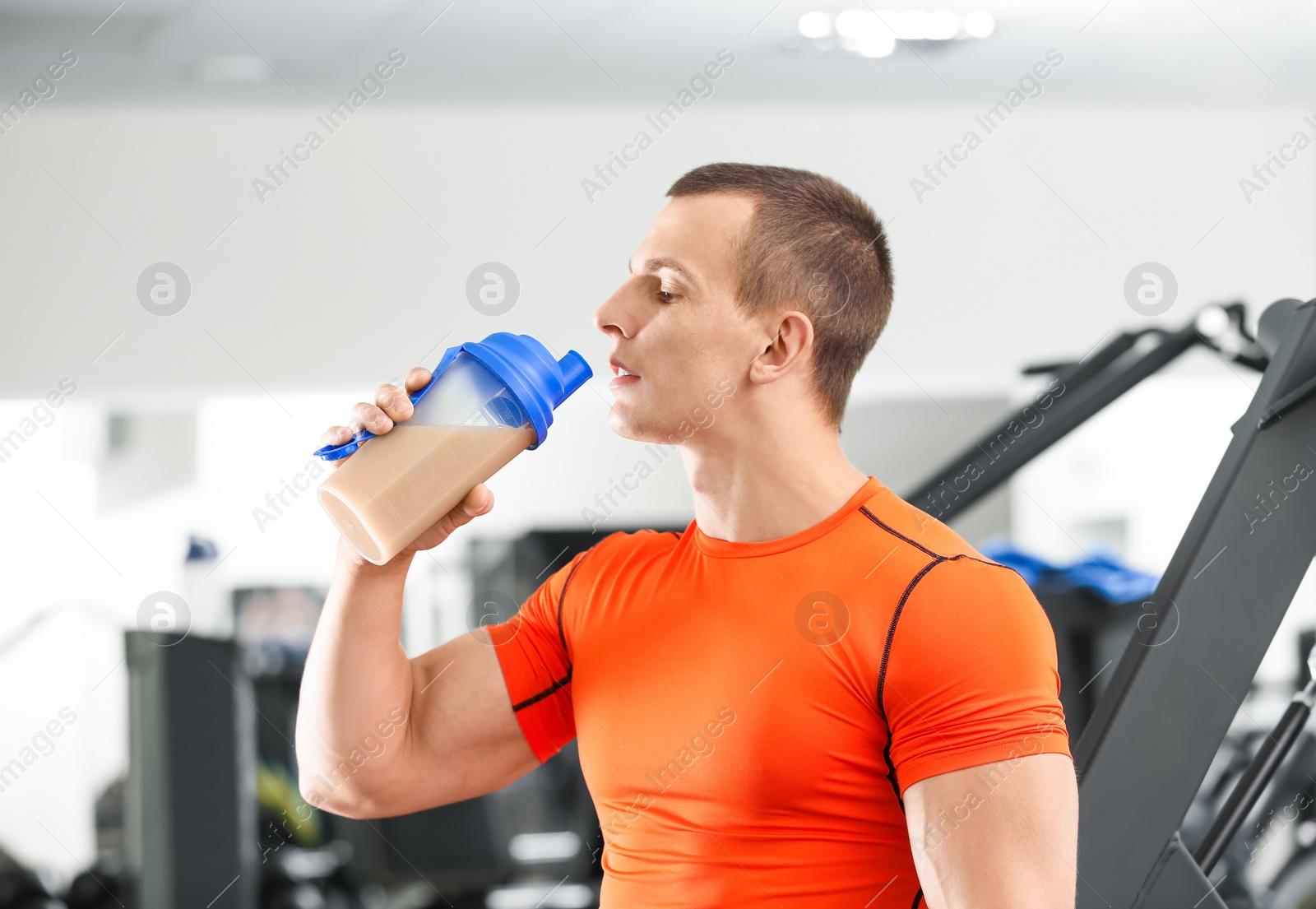 Photo of Athletic young man drinking protein shake in gym