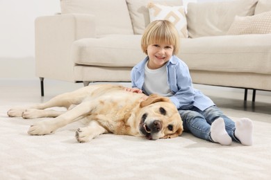 Cute little child with Golden Retriever on floor at home. Adorable pet