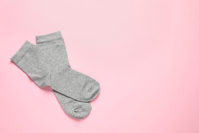 Photo of Pair of grey socks on pink background, flat lay. Space for text
