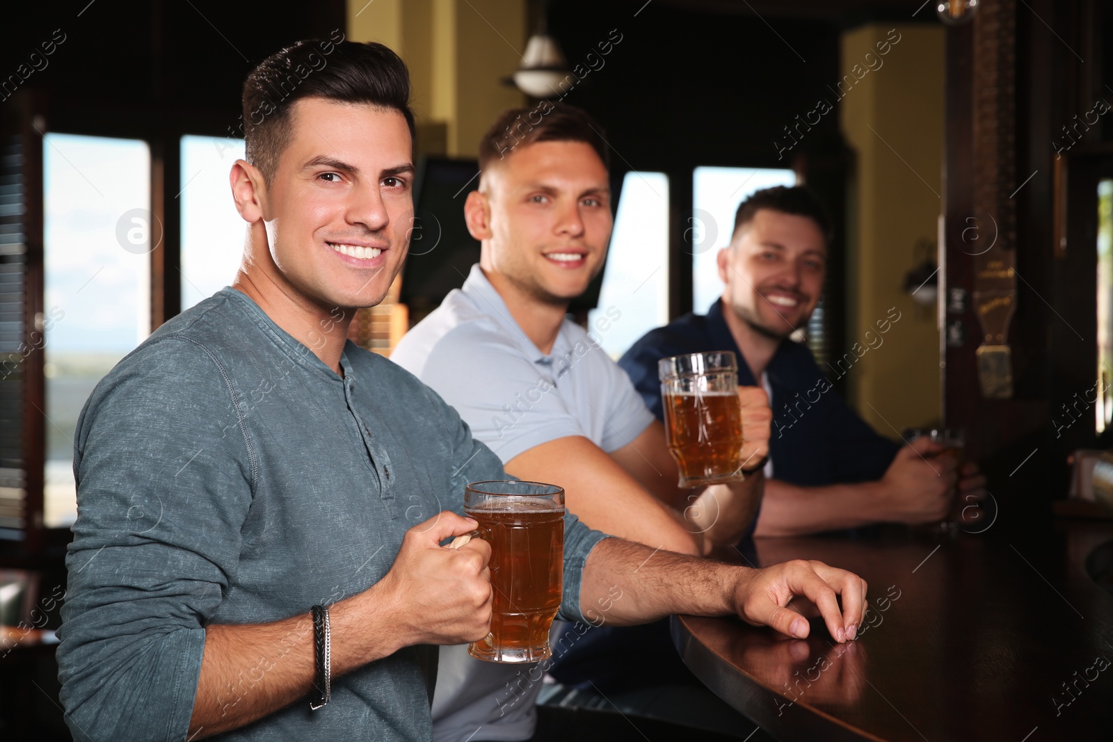 Photo of Happy friends with tasty beer in pub