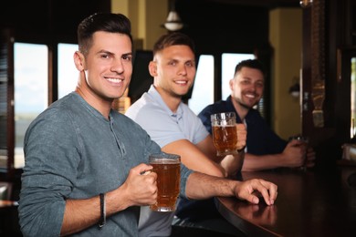 Photo of Happy friends with tasty beer in pub