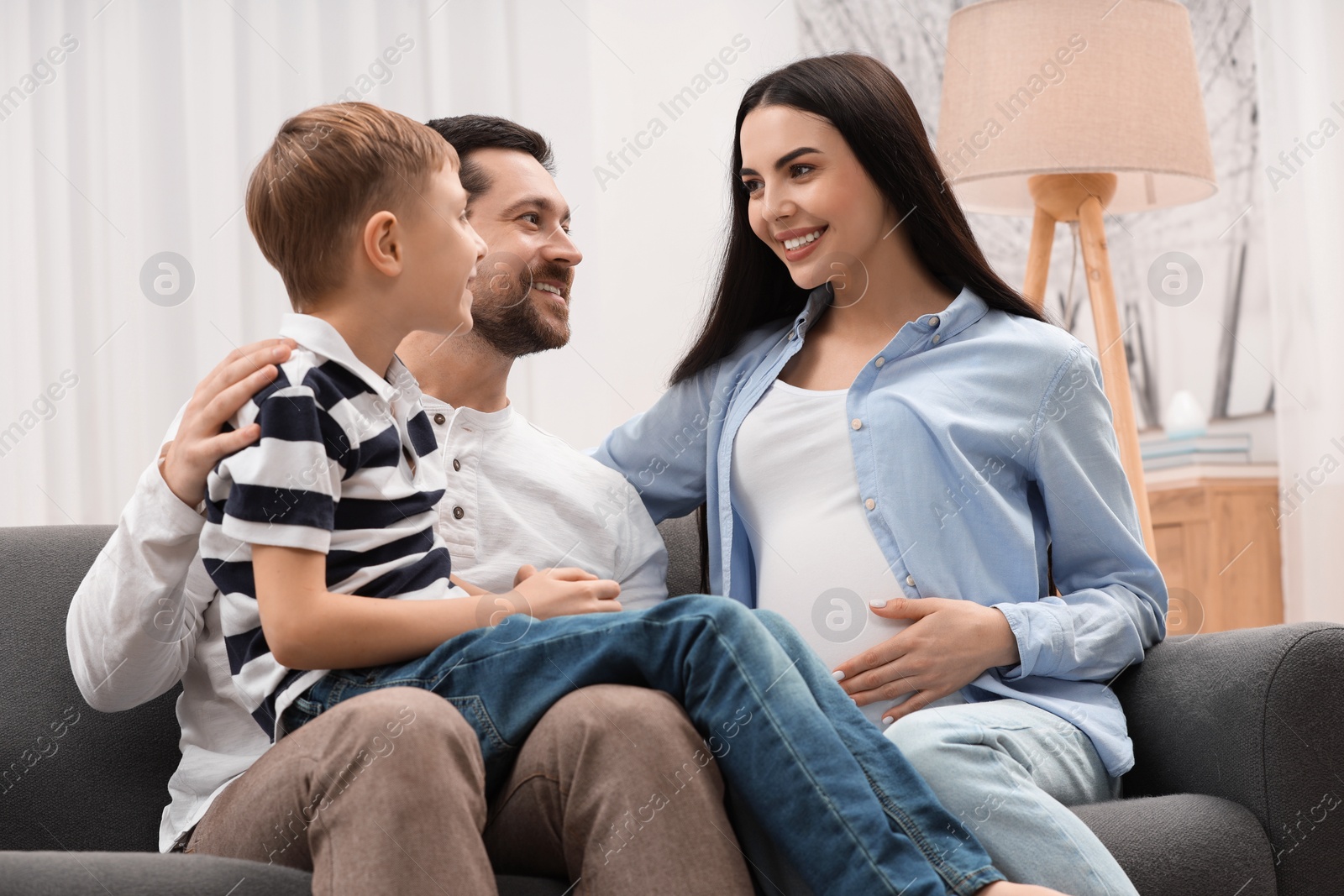 Photo of Happy pregnant woman spending time with her son and husband at home