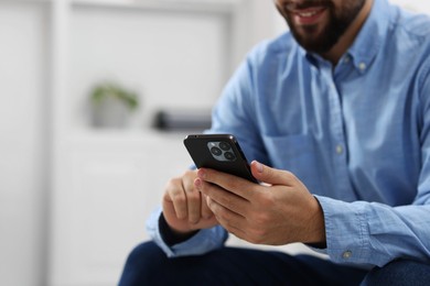 Photo of Young man using smartphone in office, closeup. Space for text