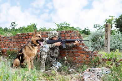 Photo of Man in military uniform with German shepherd dog at firing range