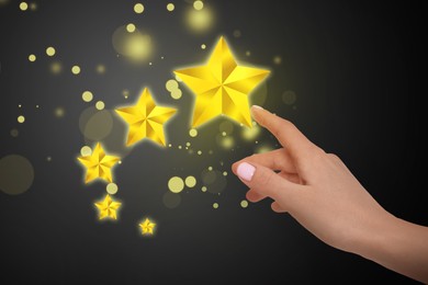 Image of Quality rating. Woman pointing at stars on black background, closeup
