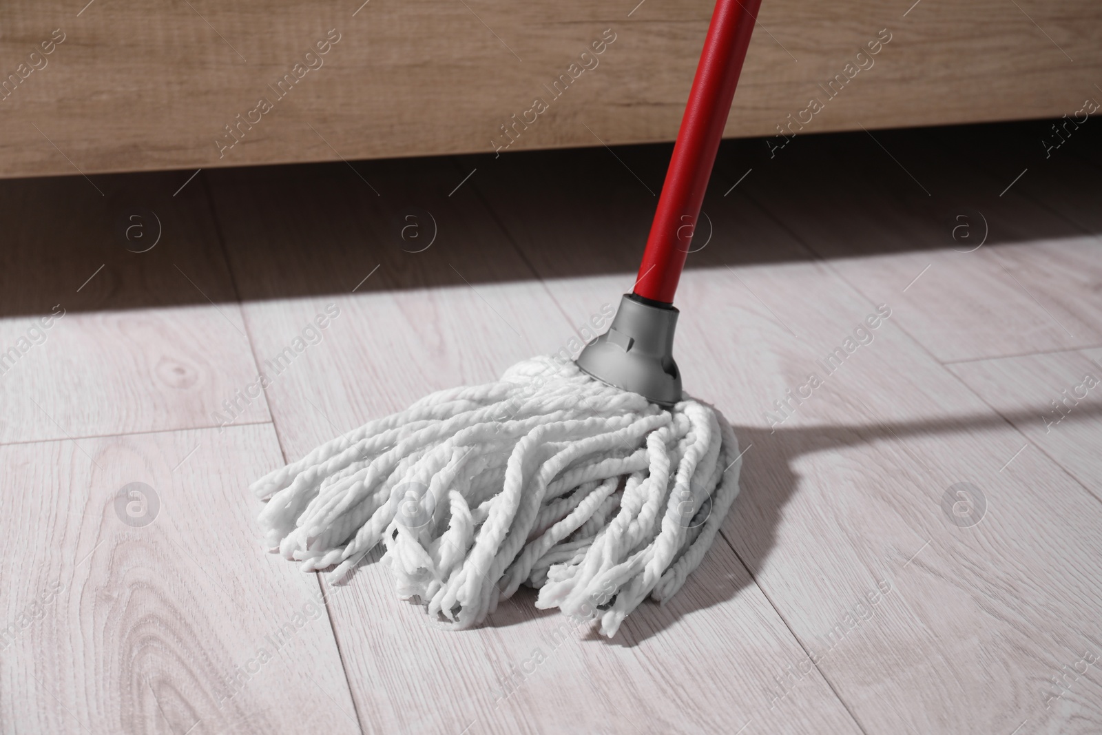 Photo of Cleaning dirty wooden floor with mop indoors