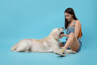 Woman with cute Labrador Retriever dog on light blue background. Adorable pet