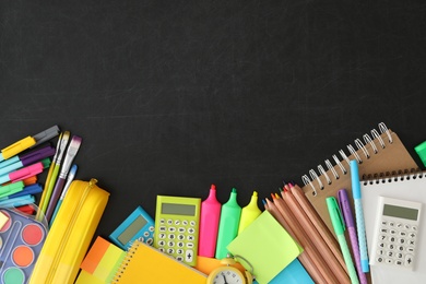 Flat lay composition with different school stationery on blackboard, space for text. Back to school