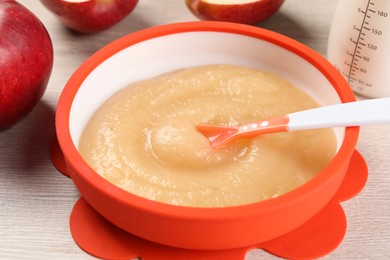 Photo of Healthy baby food. Bowl with delicious apple puree on white wooden table, closeup